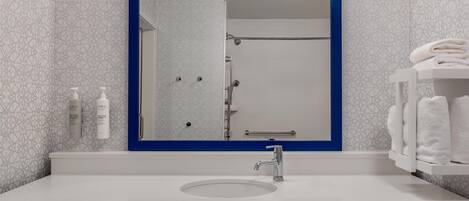 Un baño con un lavamanos blanco, un espejo con marco azul y un perchero.