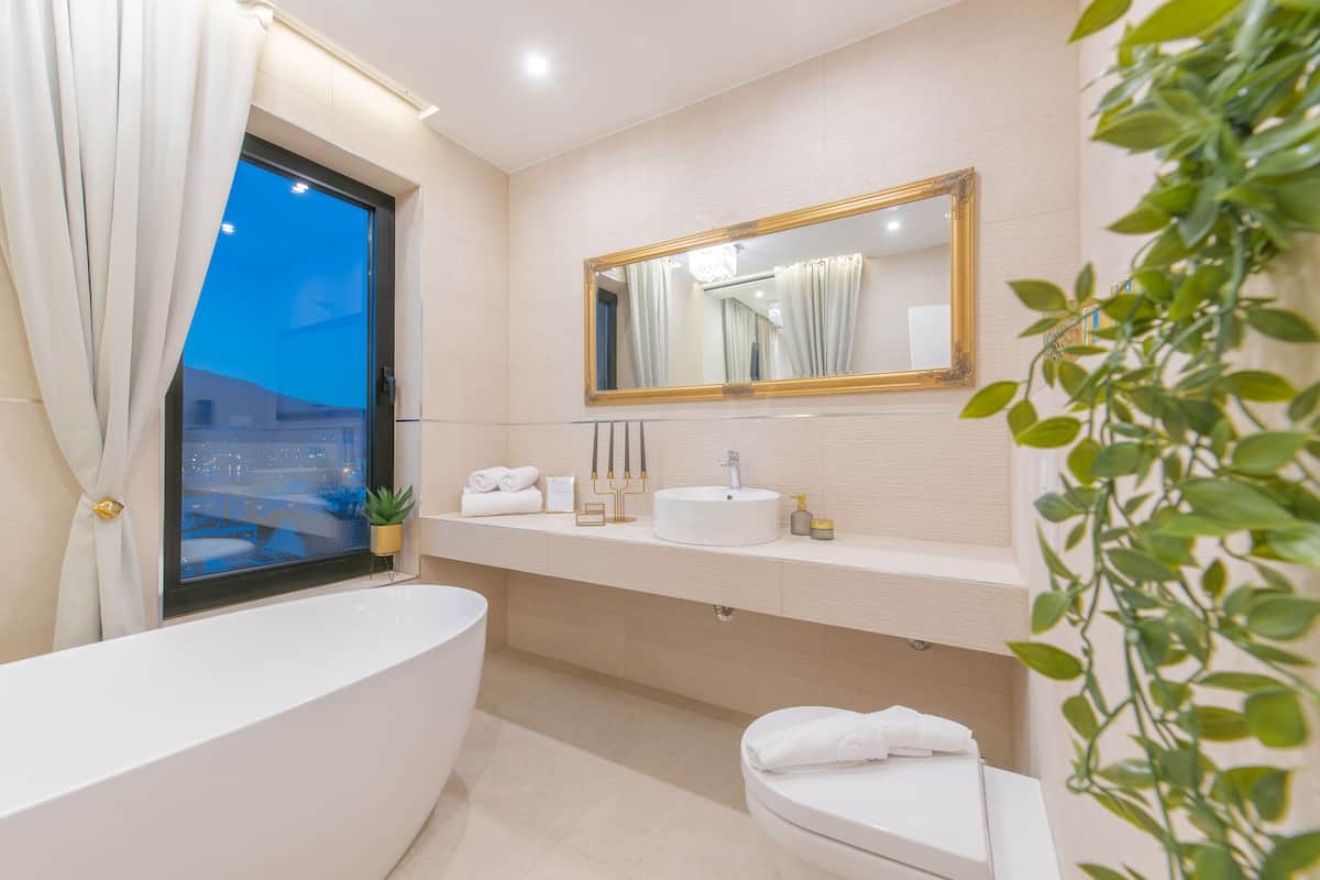 A modern bathroom with a bathtub, a sink, a toilet, and a large mirror.