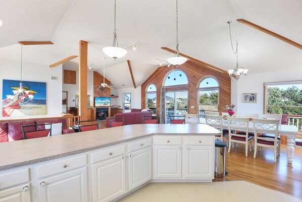 Un'ampia cucina con un'isola centrale, travi in legno e illuminazione a sospensione.