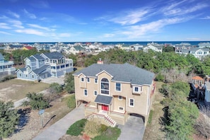 A two-story house with a red front door, a balcony, and a garage.