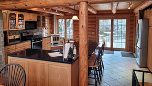 A spacious kitchen with wooden cabinetry, a central island, and a large window providing a view of the outdoors.