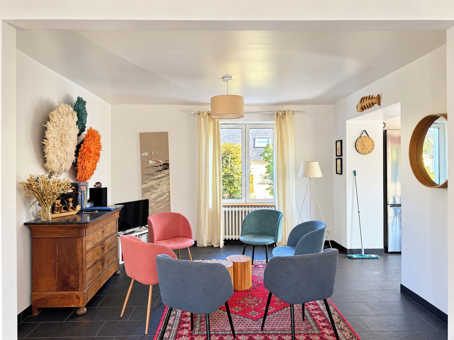A modern living room with a wooden cabinet, a flat-screen TV, and a red rug.