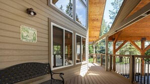 A wooden deck with a bench, large windows, and a welcome sign. - Southgate Getaway of Yosemite (Fish Camp)