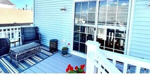 Une maison bleue avec un porche, un banc et un pot de fleurs.