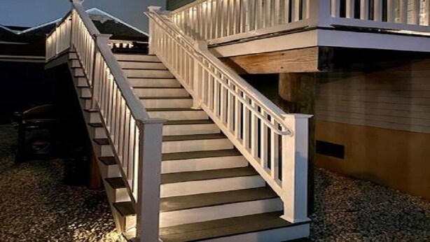 Un escalier en bois avec des rampes blanches menant à une terrasse.