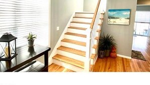 Un escalier avec des marches en bois et des rampes blanches, menant à l’étage supérieur.