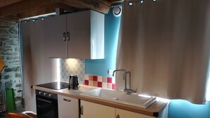 Una cocina compacta con lavamanos, estufa y alacenas.