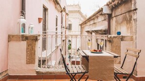 Un balcon avec une table et des chaises, une balustrade et une vue sur un bâtiment historique.
