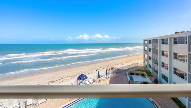 Un hotel con piscina, vista sulla spiaggia e un edificio a più piani.
