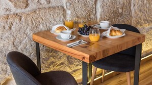 Una mesa de madera con alimentos para el desayuno, incluyendo croissants, un vaso de jugo de naranja y una botella de jugo.