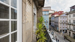 A street view with buildings featuring traditional architecture, a clear sky, and pedestrians. - GuestReady - Grandeur River Balcony Reborn (Porto)