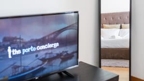 A television displaying 'the port concierge' with a bed and pillows in the background. - GuestReady - Daisy boutique (Porto)