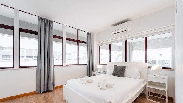 A modern hotel room with a large bed, two bedside tables, a desk, and a window with curtains. - GuestReady - Paragon in Porto (Porto)