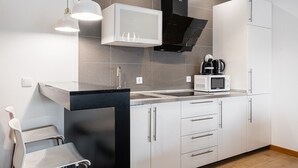 A modern kitchen with a black range hood, white cabinets, a microwave, and a coffee maker. - GuestReady - Paragon in Porto (Porto)