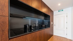 A modern kitchen with a black countertop, wooden cabinets, and a built-in microwave. - GuestReady - Hemisphere Apt (Porto)