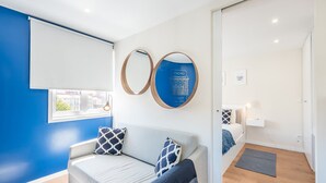 Un salon moderne avec un canapé, deux miroirs décoratifs et une vue sur l’extérieur.