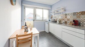 Une cuisine moderne avec des meubles blancs, une table à manger en bois et un pare-feu décoratif.