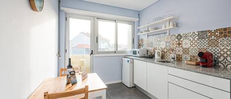 Una cocina moderna con armarios blancos, una mesa de comedor de madera y un salpicadero con diseño.