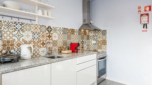 Une cuisine moderne avec des carreaux décoratifs, des meubles blancs, une hotte en acier inoxydable et un four encastré.