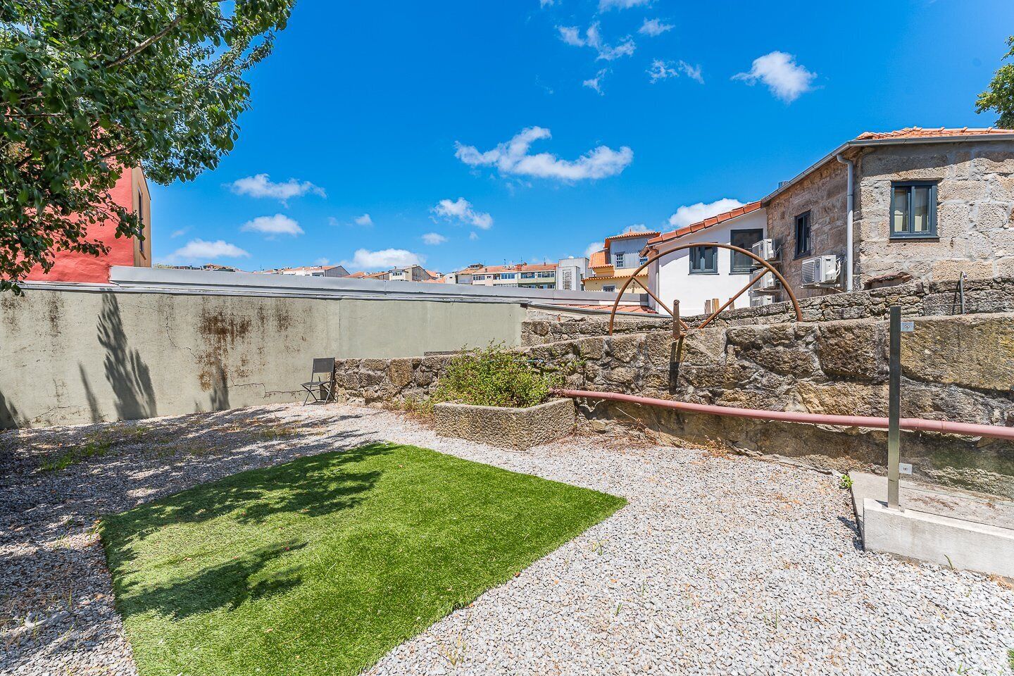 Un patio con césped, un muro de piedra y un edificio con techo de tejas.