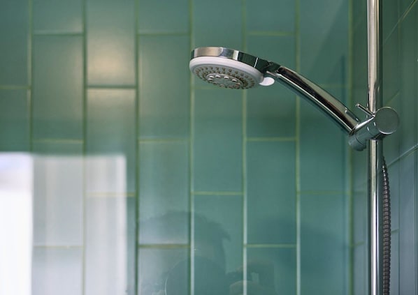 Un cabezal de ducha con un mango curvo, fijado a una pared con diseño de azulejos.