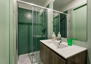 A bathroom with a glass shower enclosure, a white sink, and a mirror. - GuestReady - Porto Home II (with balcony) (Porto)