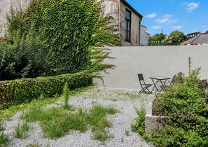 A courtyard with a gravel path, a hedge, and two black chairs. - GuestReady - Porto Home II (with balcony) (Porto)