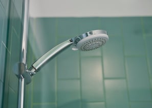 Un cabezal de ducha con diseño redondo y perforado, montado sobre una estructura de cromo.