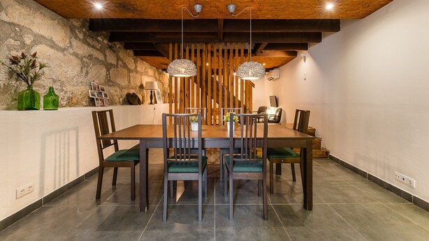 Een eetruimte met een houten tafel, stoelen en hangende lampen.
