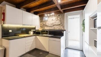 Una cucina compatta con mobili bianchi, un piano di lavoro in granito e una parete decorativa in pietra.
