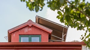 Een gebouw met een rood dak en groene raamkozijnen.