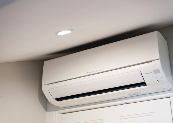 A Mitsubishi Electric air conditioner mounted on a wall above a white door.