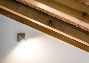 A ceiling with exposed wooden beams and a recessed light fixture.