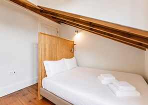 A bedroom with a wooden headboard, a bed, and a wall-mounted light fixture.