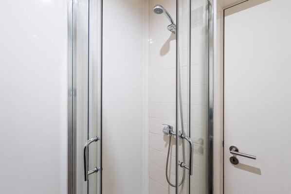 A glass-enclosed shower stall with a handheld showerhead and a handheld shower hose. - GuestReady - MusicHall - The Phantom of the Opera (Porto)