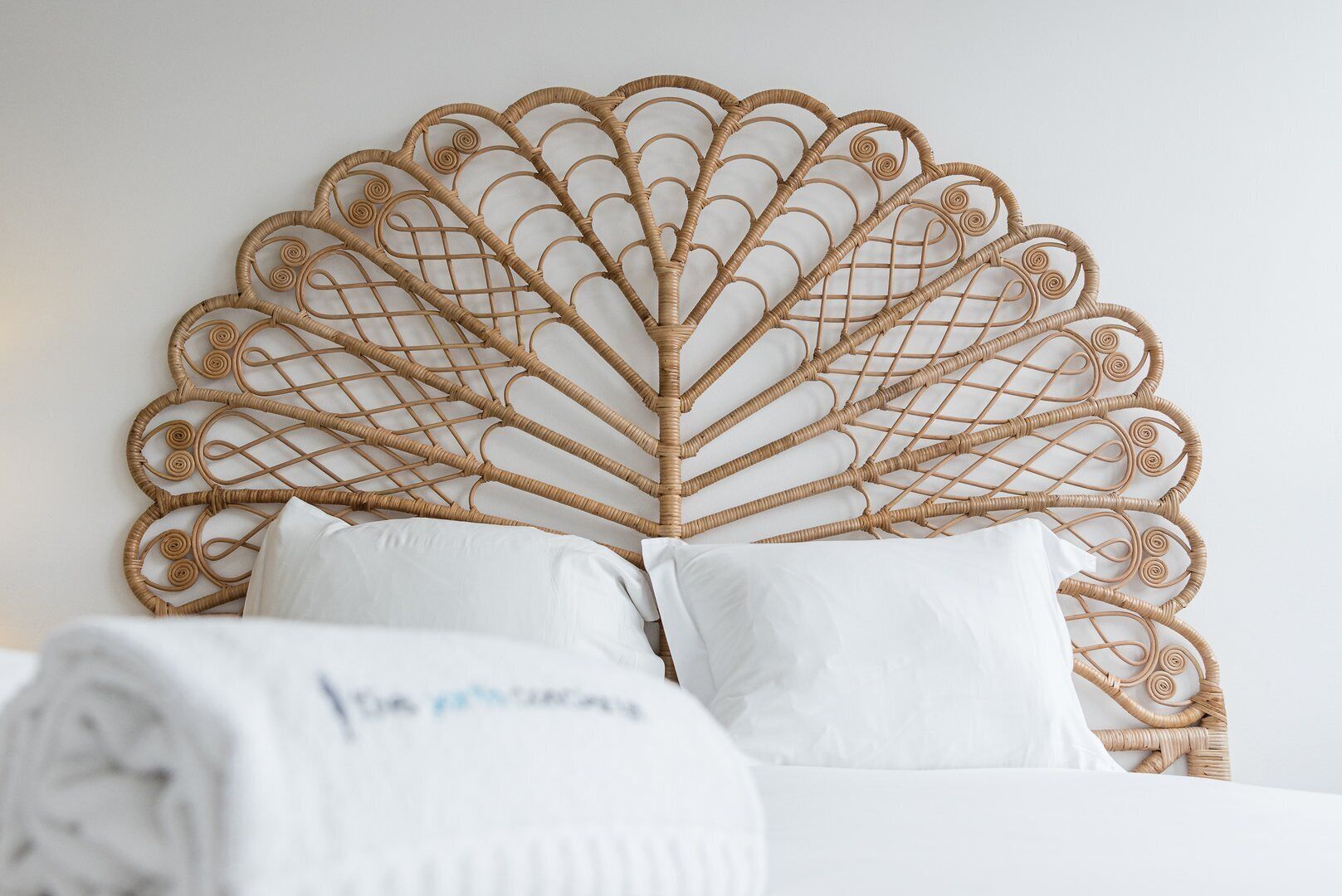 A bed with a woven headboard and white bedding.
