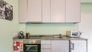 Une cuisine compacte équipée d’un four encastré, d’un four à micro-ondes et d’un évier.