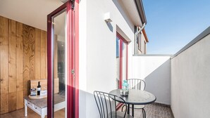 A small outdoor balcony with a wooden bench, a table with chairs, and a bottle of wine. - GuestReady - Crayon Walls 3rd (Porto)