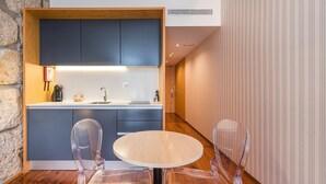 Une cuisine moderne avec des meubles bleus, un plan de travail en bois et une table ronde entourée de chaises transparentes.