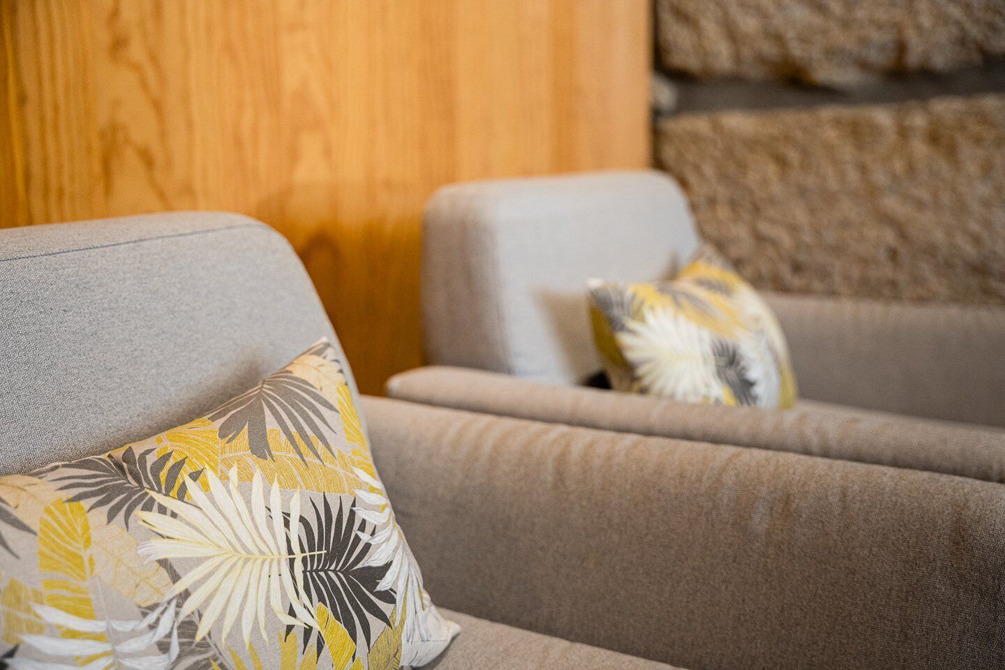 A seating area with two grey sofas and a patterned throw pillow.