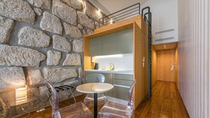 A modern kitchen with a stone wall, wooden cabinets, and a round table with clear chairs.
