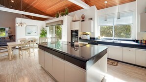 A modern kitchen with a central island, white cabinetry, and a wooden ceiling. - 5BR Palmetto Dunes • Golf View • FREE Heated Pool (Hilton Head Island)