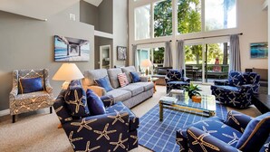 A spacious living area with a large window, a grey sofa, patterned armchairs, and a coffee table. - 5BR Palmetto Dunes • Golf View • FREE Heated Pool (Hilton Head Island)