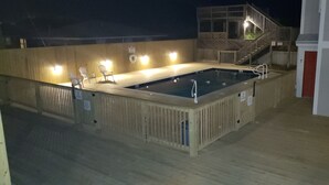 Uma piscina com deck de madeira, uma escadaria e um prédio com o número 7.