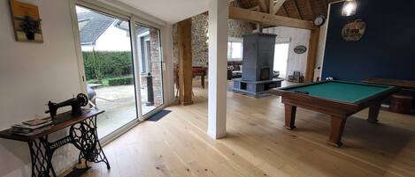 A spacious room with a pool table, a sewing machine, and a stone fireplace.