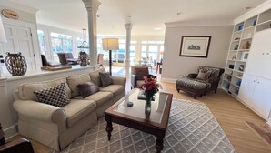Un salon spacieux avec un canapé beige, une table basse ornée d’un vase et un tapis à motifs.