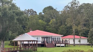 Un chalet au bord du lac, avec un toit rouge, une véranda et une terrasse.