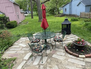 A patio with a round table and chairs, a red umbrella, and a lantern. - Grand Victorian Carlinville home on Rt. 66.  (Carlinville)