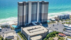 A high-rise hotel with multiple floors, a parking garage, and a beach view.