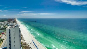 A coastal hotel with a beach view, a pier, and a clear blue sky.